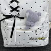White corduroy backpack with black polka dots featuring a fuzzy gray bear charm and zipper pockets