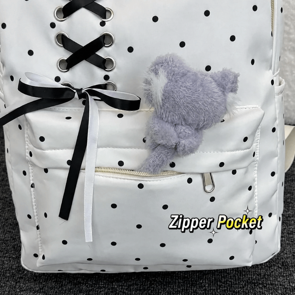 White corduroy backpack with black polka dots featuring a fuzzy gray bear charm and zipper pockets