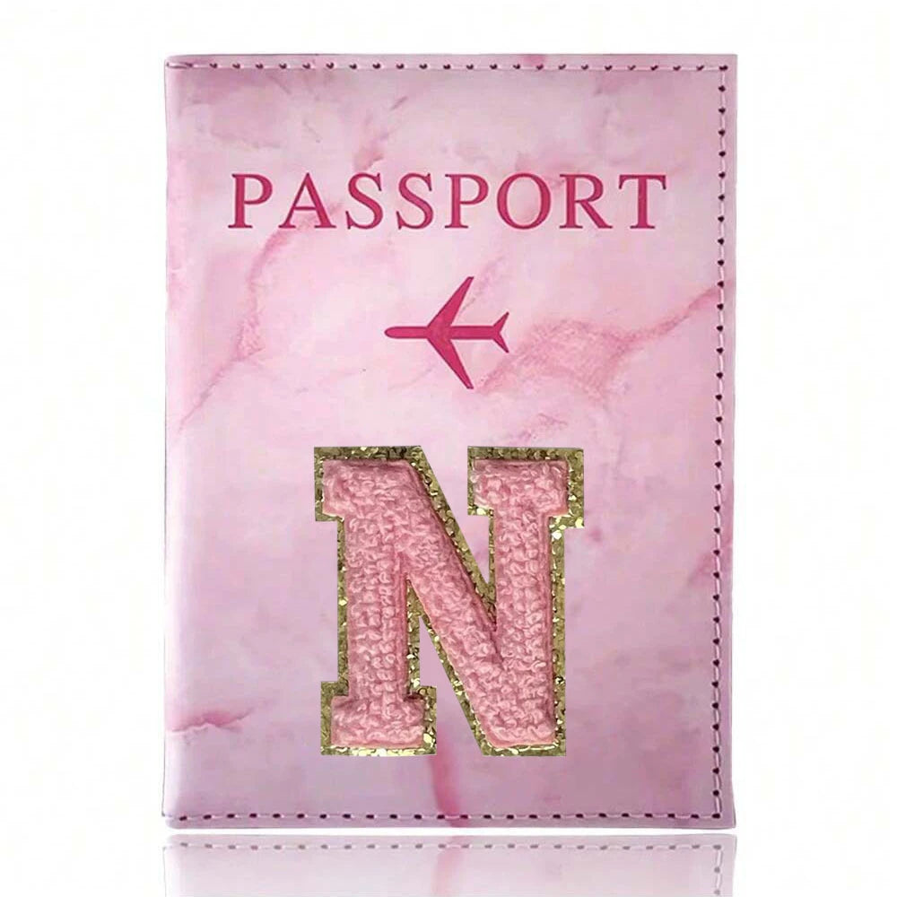 A pink marbled leather passport cover featuring a gold embroidered letter N