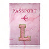 A pink marbled passport cover featuring a gold initial L and a pink airplane emblem.