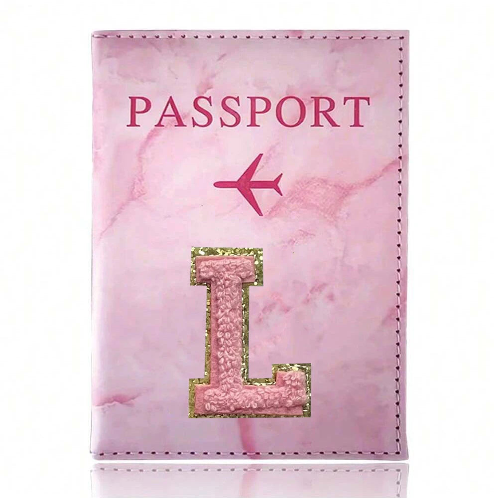 A pink marbled passport cover featuring a gold initial L and a pink airplane emblem.