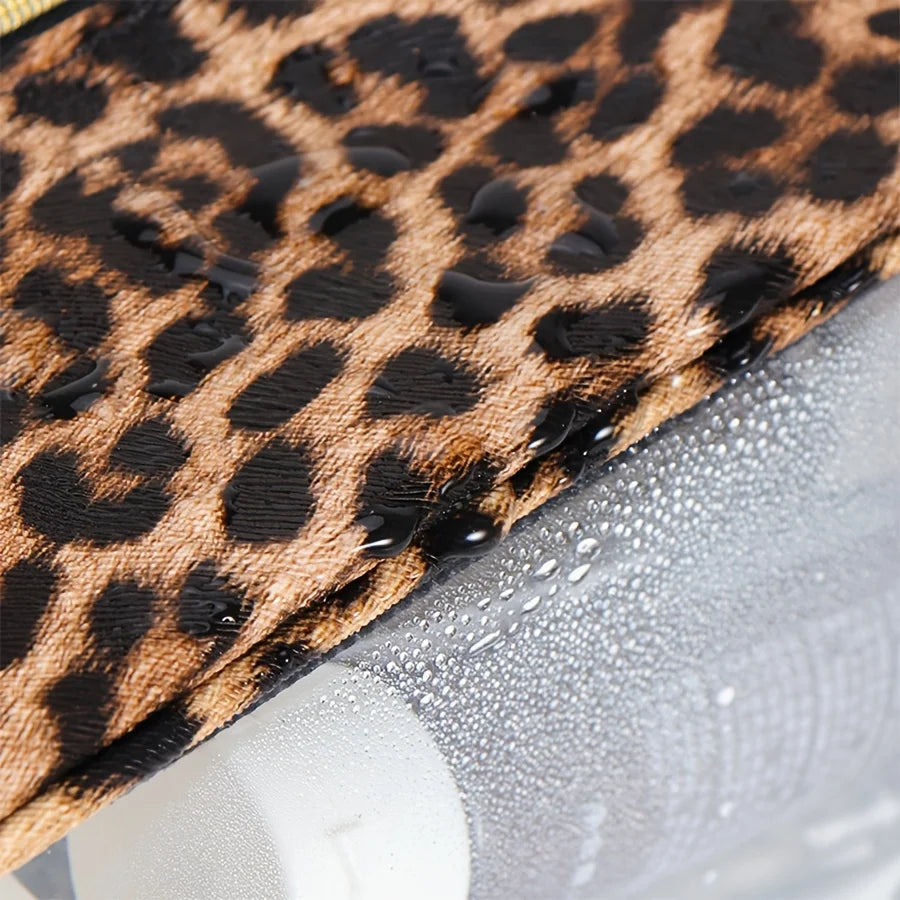 A close-up of a leopard print fabric being placed inside a clear cosmetic bag.