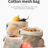 A collection of reusable cotton mesh bags filled with various produce like corn, eggplant, and apples.
