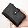 A hand holds a black leather clutch wallet with an RFID protection feature.