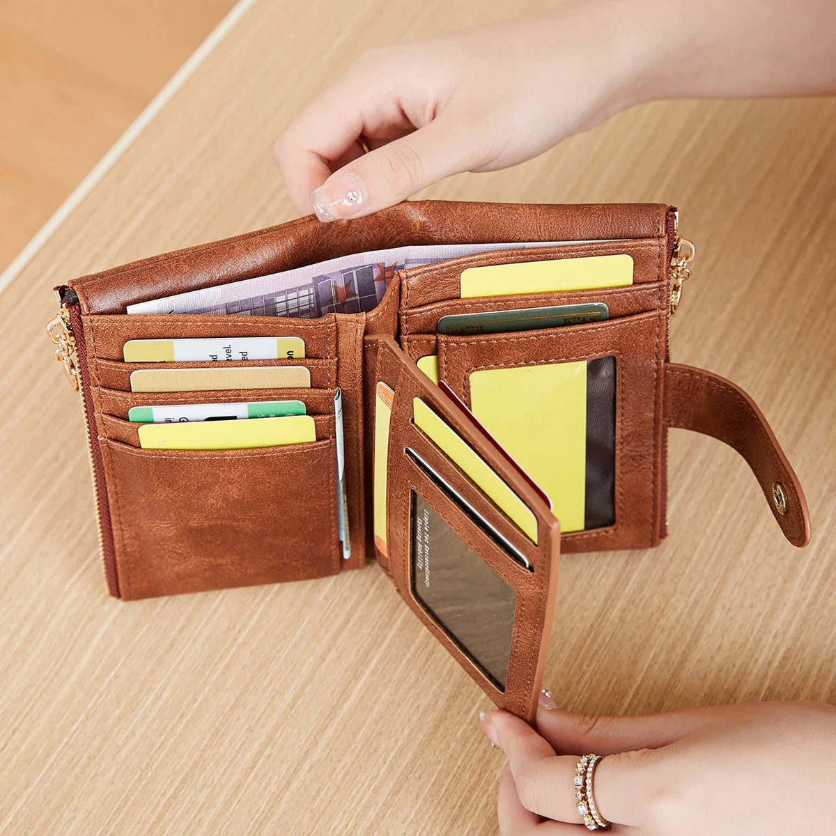 A brown leather wallet with a gold clasp is shown open, displaying various cards and cash inside.