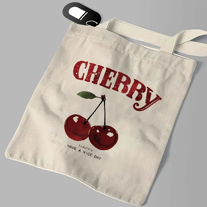 A beige canvas shoulder tote bag featuring a red cherry print with the text Have a Nice Day.