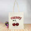 A cream canvas tote bag with a red cherry print and the text Happy Have a Nice Day.