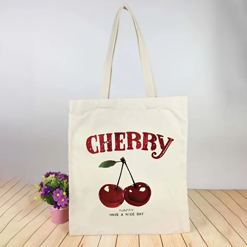 A cream canvas tote bag with a red cherry print and the text Happy Have a Nice Day.