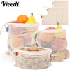 Reusable cotton mesh produce bags filled with fruits like oranges and lemons
