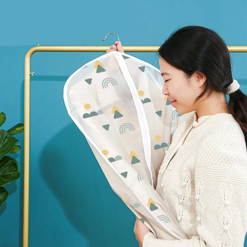 A woman is placing a clear garment dust cover on a hanger, which is hanging on a gold-colored rod.