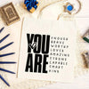 A white canvas tote bag with black text that reads You are enough brave worthy loved amazing strong capable smart kind