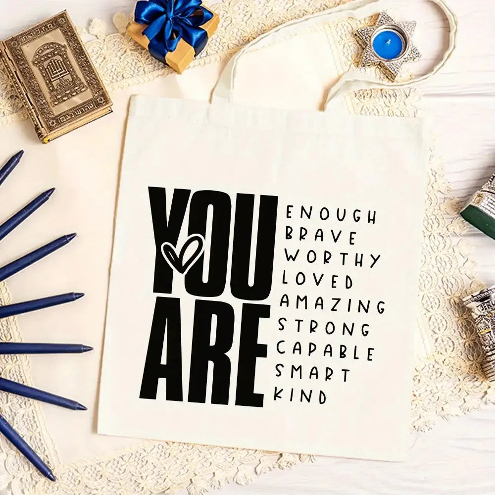 A white canvas tote bag with black text that reads You are enough brave worthy loved amazing strong capable smart kind