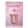 A pink marble leather passport cover featuring a gold embossed letter U and a pink airplane design.