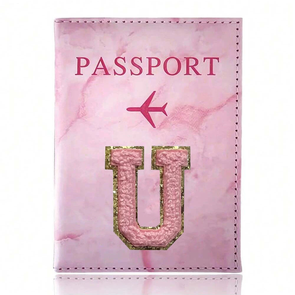 A pink marble leather passport cover featuring a gold embossed letter U and a pink airplane design.