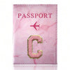 Pink marbled passport cover with embroidered gold letter C and a pink airplane symbol