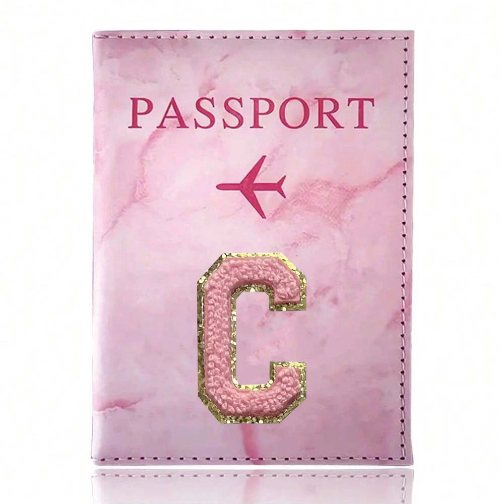 Pink marbled passport cover with a gold embroidered letter C and a pink airplane symbol