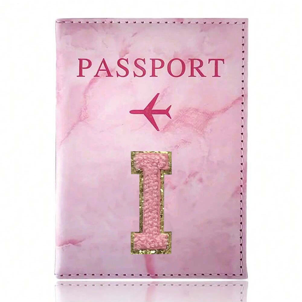 A pink marbled leather passport cover featuring gold embroidery of the letter I
