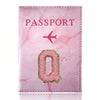 A pink marbled leather passport cover featuring a gold embroidered letter O.