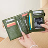 A hand holds an olive green minimalist foldable wallet with a zipper, displaying various cards and cash.