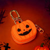 Llavero cartera de monedas de calabaza naranja tallada con hebilla plateada sobre fondo oscuro con telarañas y siluetas espel