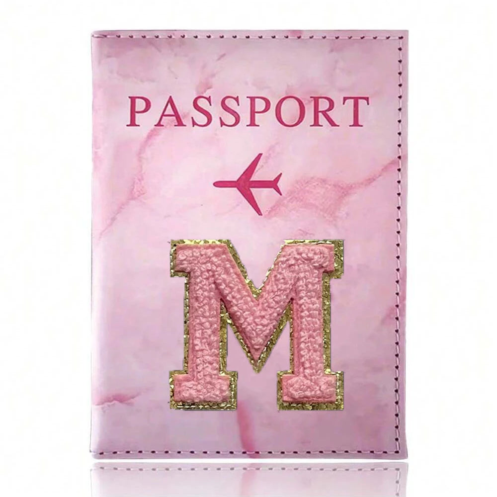 Pink marbled passport cover featuring a gold embroidered letter M and a pink airplane symbol