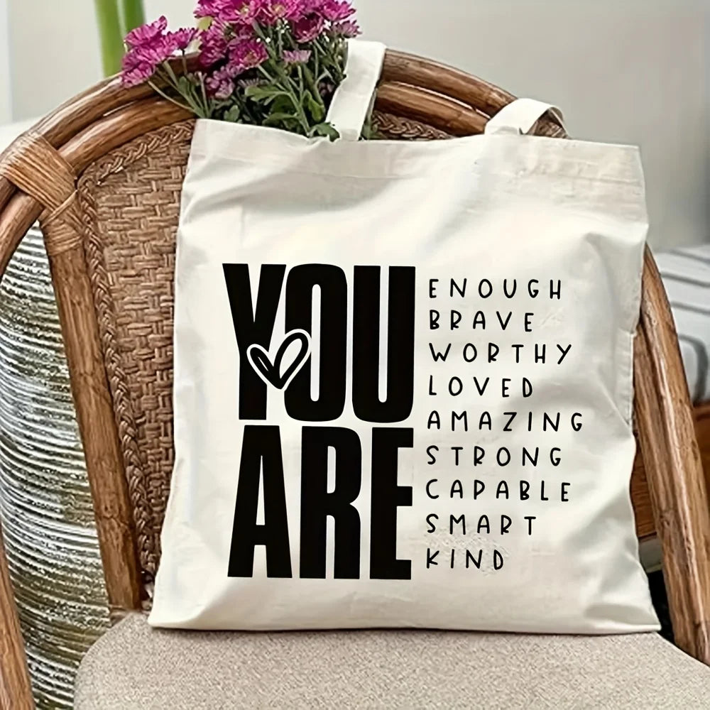 A white canvas tote bag with black text that reads You are enough brave worthy loved amazing strong capable smart kind