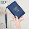 A hand holds a dark blue RFID blocking passport wallet with a gold emblem and a strap.