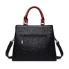 Sac bandoulière en cuir PU noir avec poignée et motif monogramme gravé.