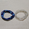 Two strands of colorful belly bead chains, one dark blue and the other clear, laid out on a light surface.