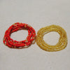 Two strands of colorful belly bead chains, one red and one gold, laid out on a white surface.
