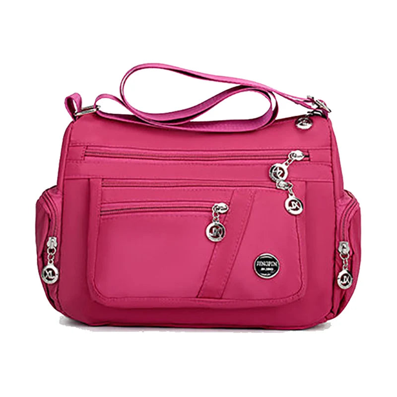 A bright pink waterproof nylon crossbody tote bag with a pink strap and silver hardware.
