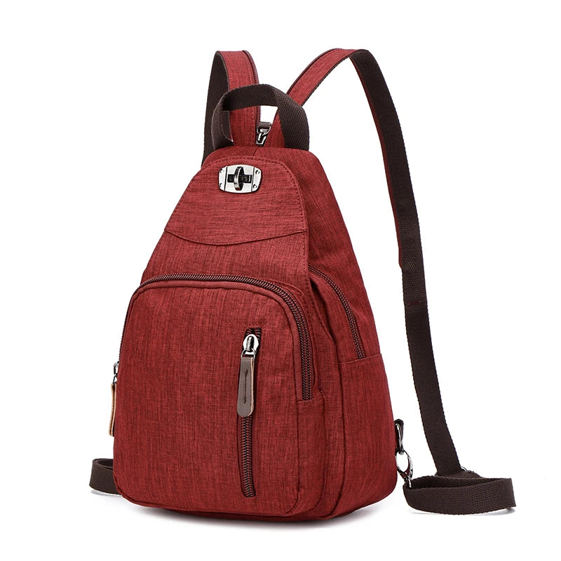 A maroon canvas backpack with a flap closure and zippered pockets, shown from the front.
