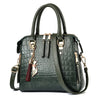 A dark green crocodile-embossed leather tassel shoulder bag with gold hardware.