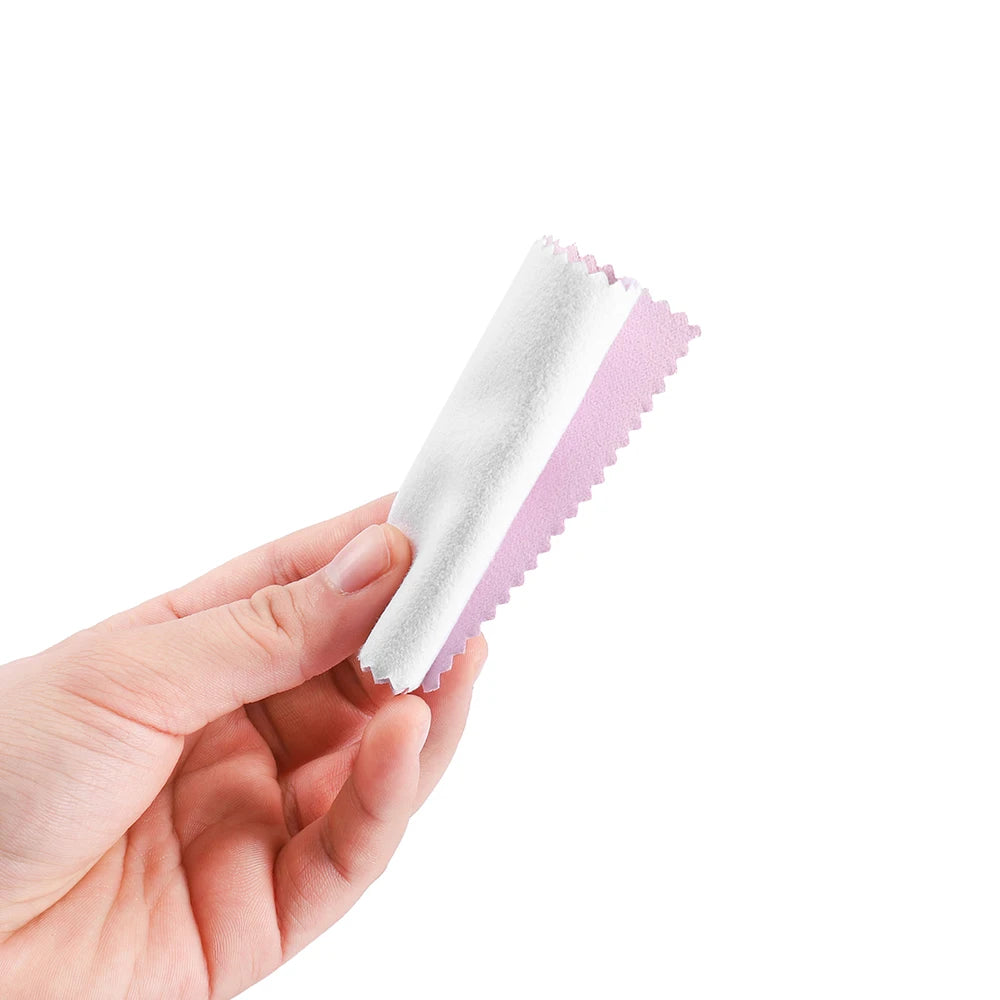 A hand holds a pink and white polishing cloth set for jewelry.