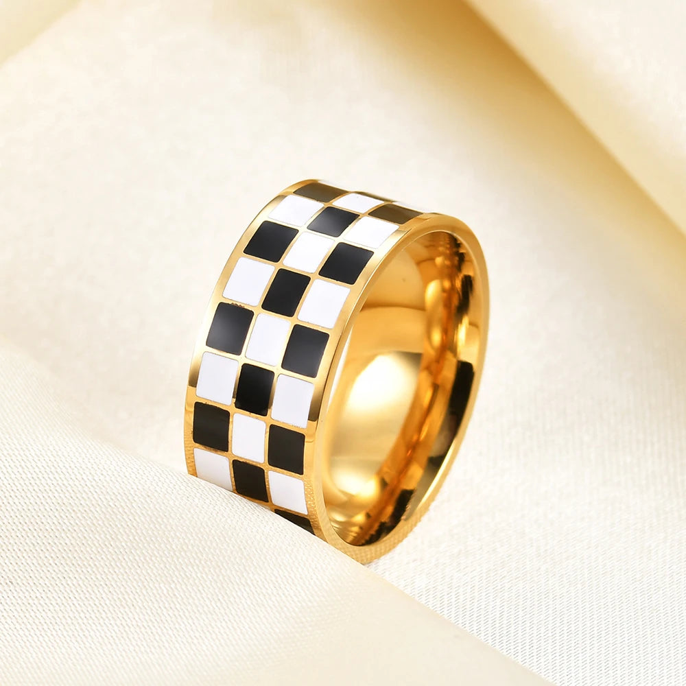Gold rings with a black and white checkerboard pattern set against a cream fabric background