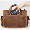 A hand is placing an passport into the zippered compartment of a brown genuine cowhide leather briefcase.