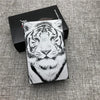 A black box holds a custom engraved cigarette case featuring a detailed white tiger face design.