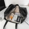 A black oversized PU leather tote bag is open, revealing a laptop and several electronic devices inside.