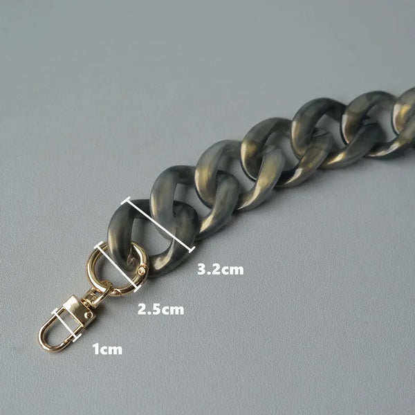 A close-up of a dark metal chain with a gold-toned clasp and various length measurements.