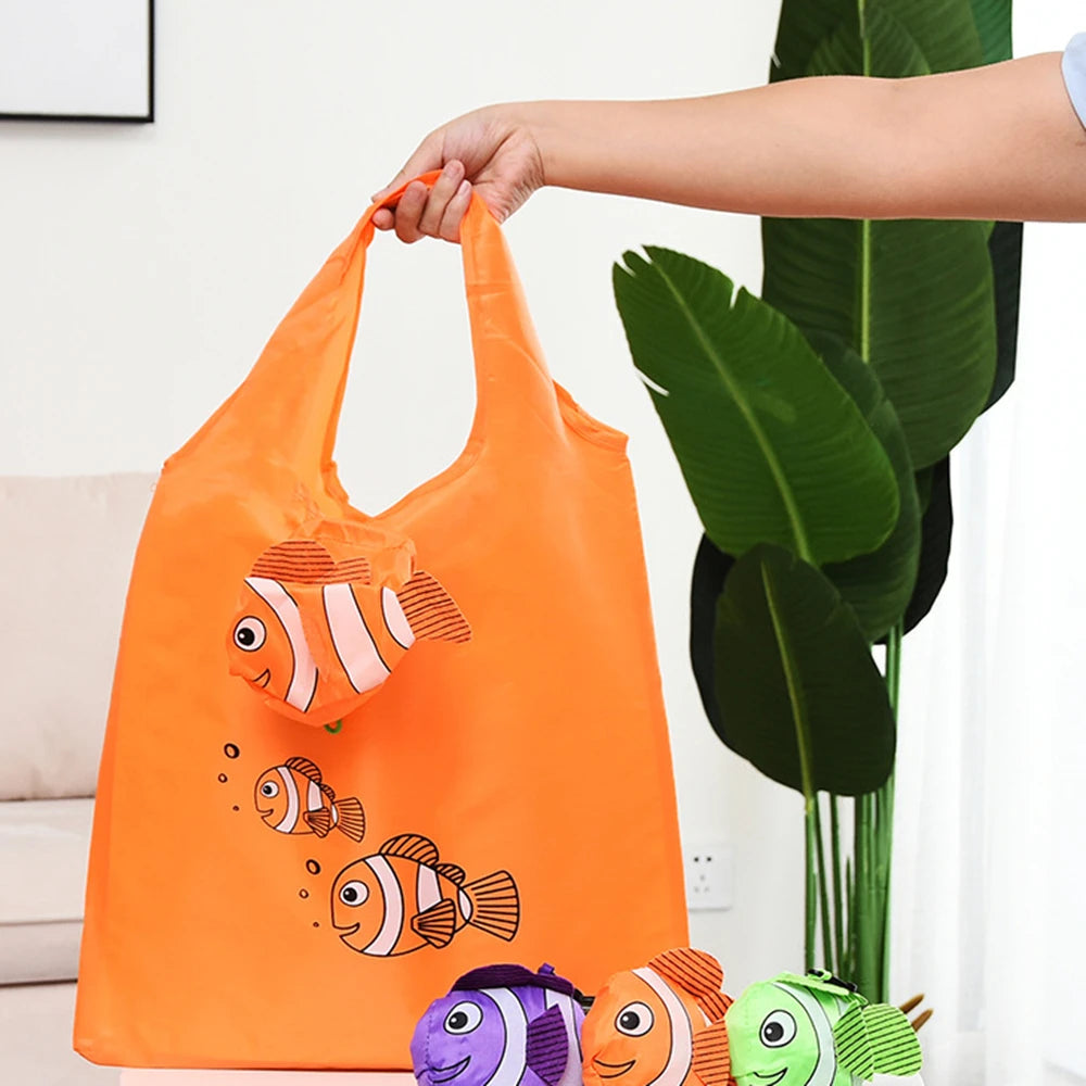 Un sac de shopping orange, pliable et écologique, avec des dessins de poissons, tenu par une main.