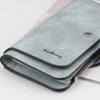 A light blue suede card holder wallet with a black trim and silver clasp resting on a white surface.