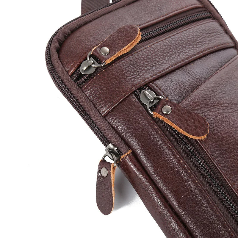 A close-up view of a brown genuine leather crossbody phone pouch belt bag with zippered compartments.