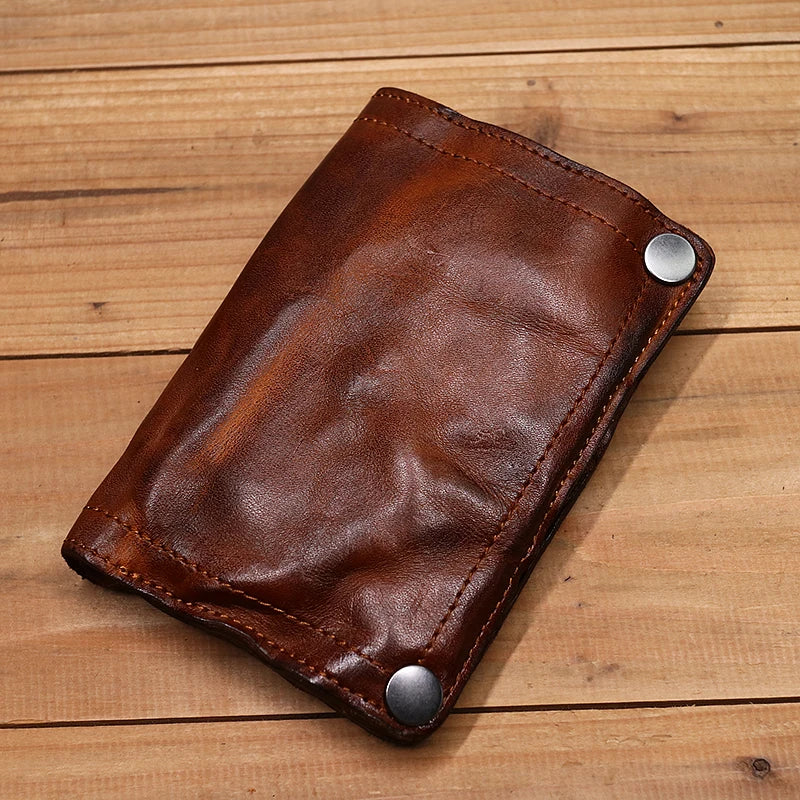 Braunes Leder-Etui zum Falten mit silbernen Schnallen auf einer Holzoberfläche