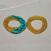 Two strands of colorful belly bead chains, featuring turquoise and gold beads, laid out on a light surface.