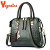 A dark green crocodile-embossed leather tassel shoulder bag with gold hardware.
