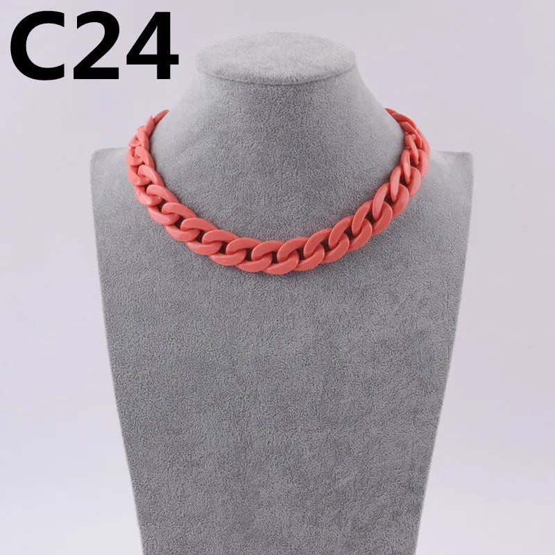 A close-up of a coral pink acrylic link chain necklace displayed on a mannequin neck.