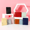 A collection of six compact PU leather zip wallets in various colors displayed on a white stand.