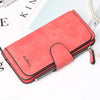 A coral red card holder wallet with a zipper is shown next to some papers and a pearl necklace.