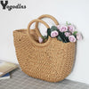 A handwoven straw moon bag with top handles in a natural tan color, displayed against a white background.