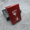 A red custom engraved cigarette case featuring a wolf head design, resting on a gray textured surface.